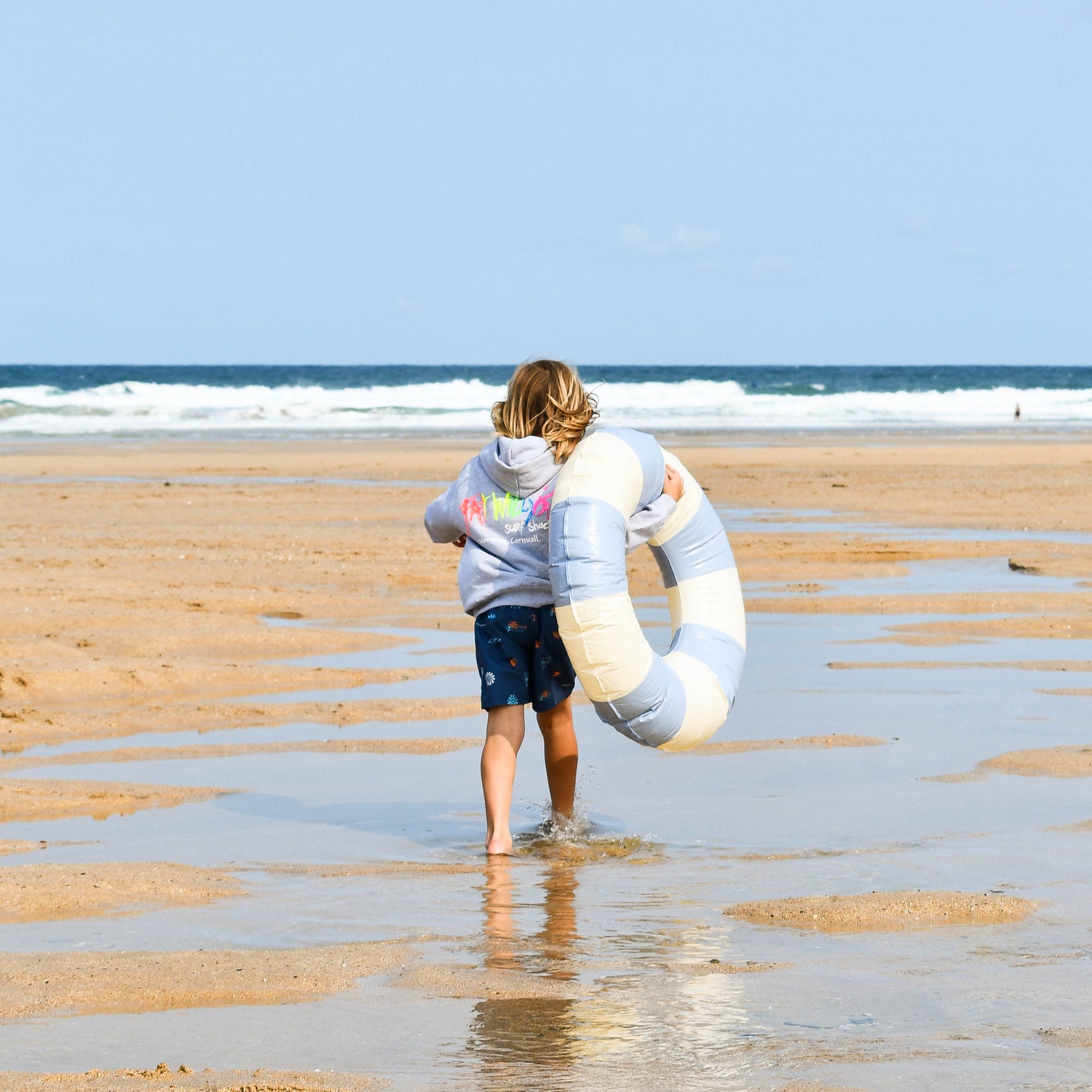 Person walking on a beach with an inflatable ring