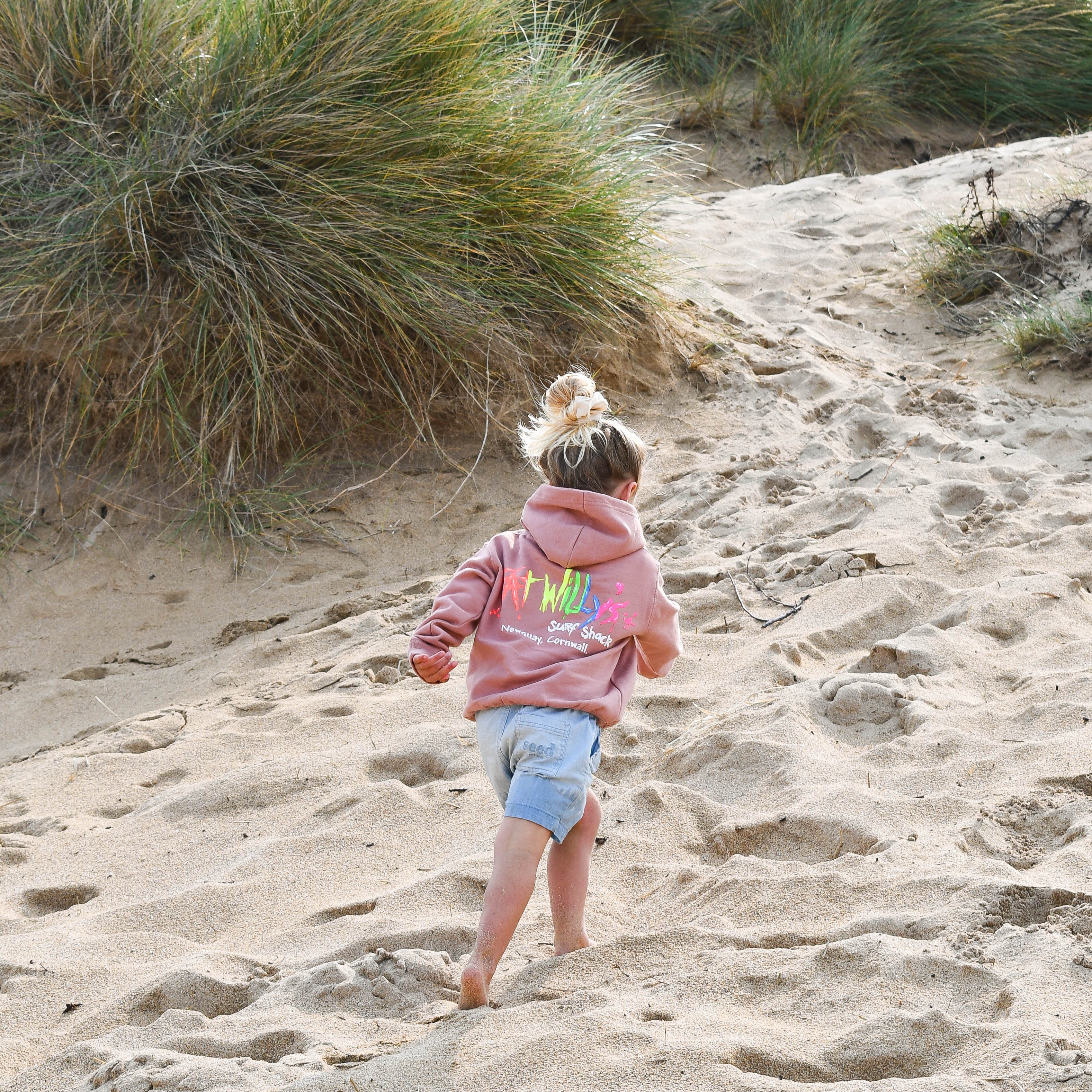 Child walking on a sandy path with grasses in the background
