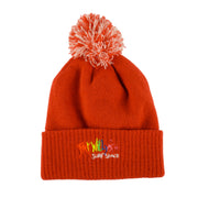 red knit beanie with pom-pom on a beige background