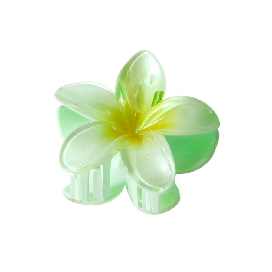 Floral hair clip with green and yellow petals on a white background